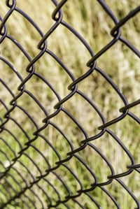 Receding pattern of chain-link fence (shallow depth of field), for themes of dependability, safety, protection, and transparency